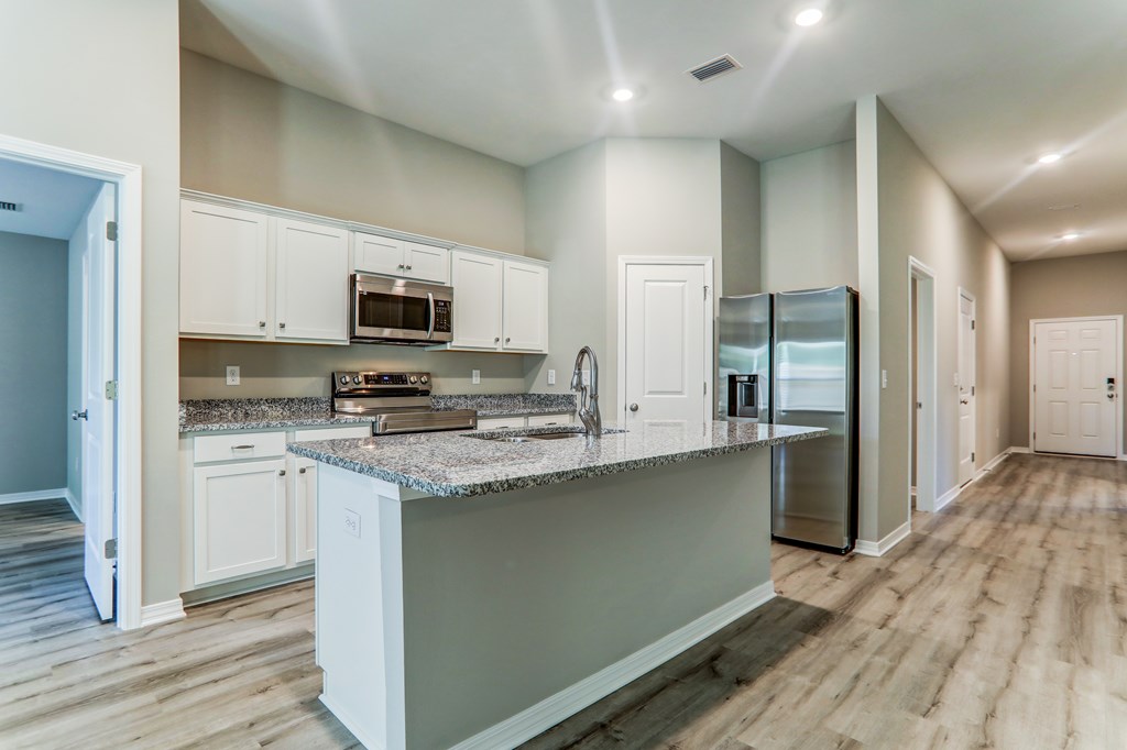 a kitchen with white cabinets and a marble counter top