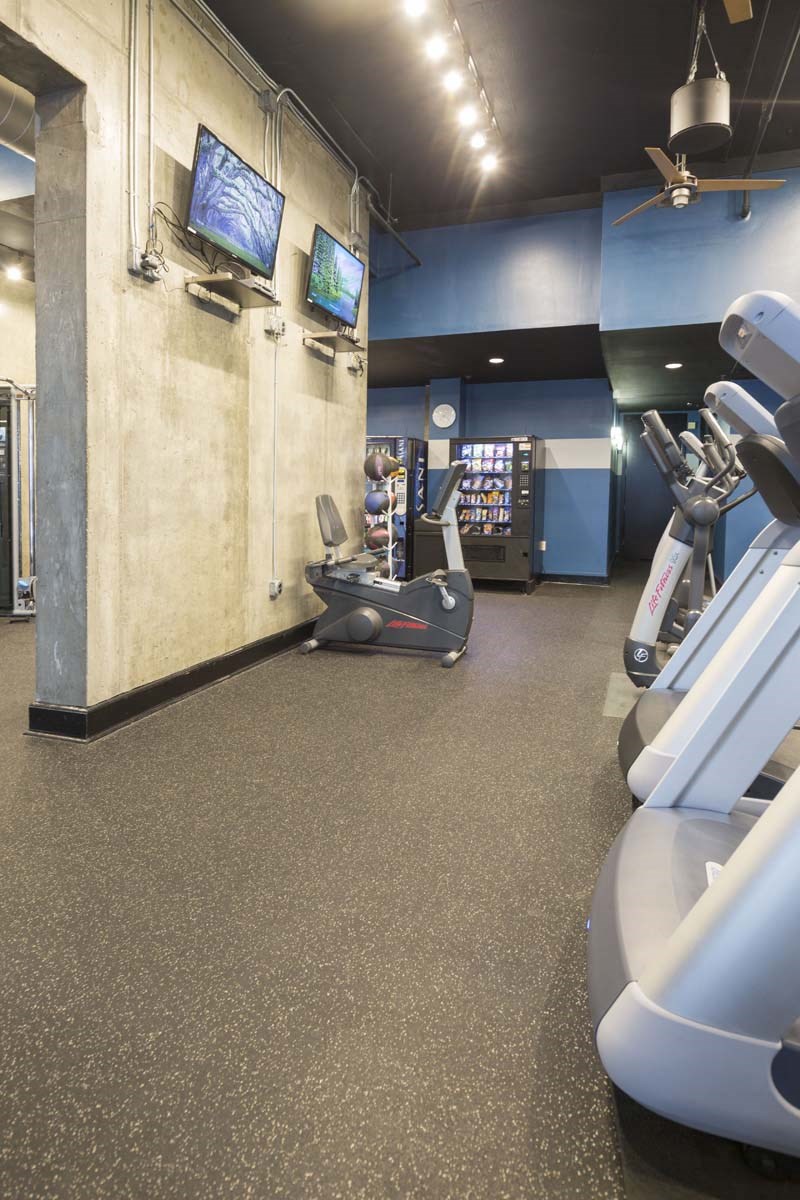 a gym with a treadmill and a tv on the wall