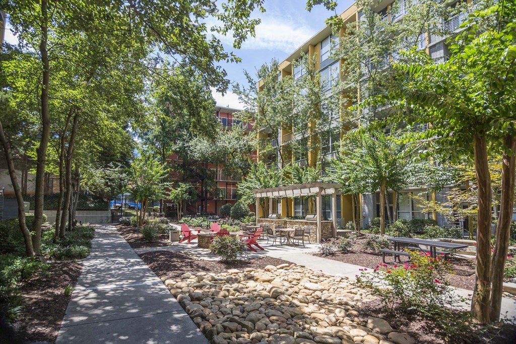 a courtyard with trees and rocks and a building in the background