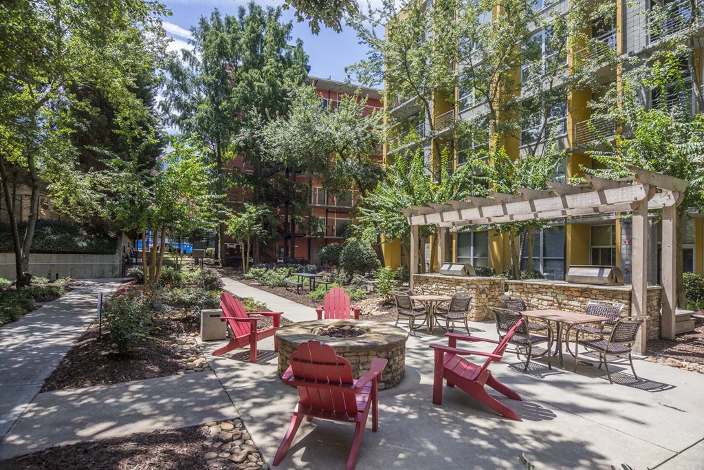 a patio with red chairs and a fire pit in front of a building