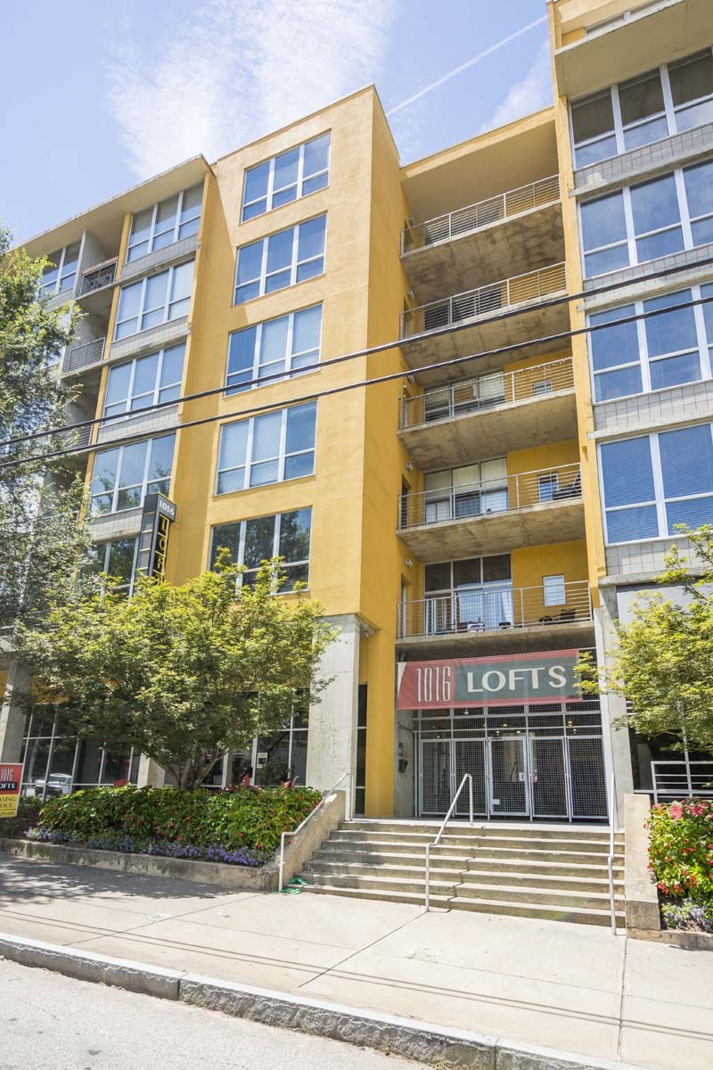 an apartment building with yellow walls and a red sign that says little loftes