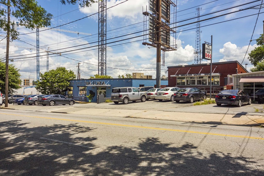 a small blue building with a red roof and a parking lot with cars in front of it