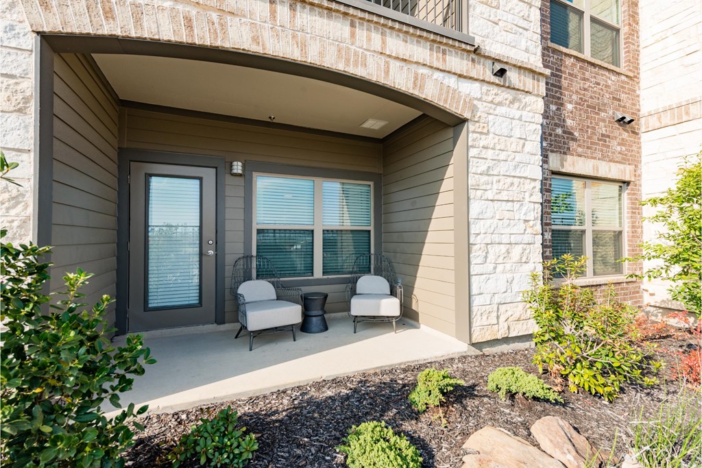 a covered porch with two chairs in front of a building