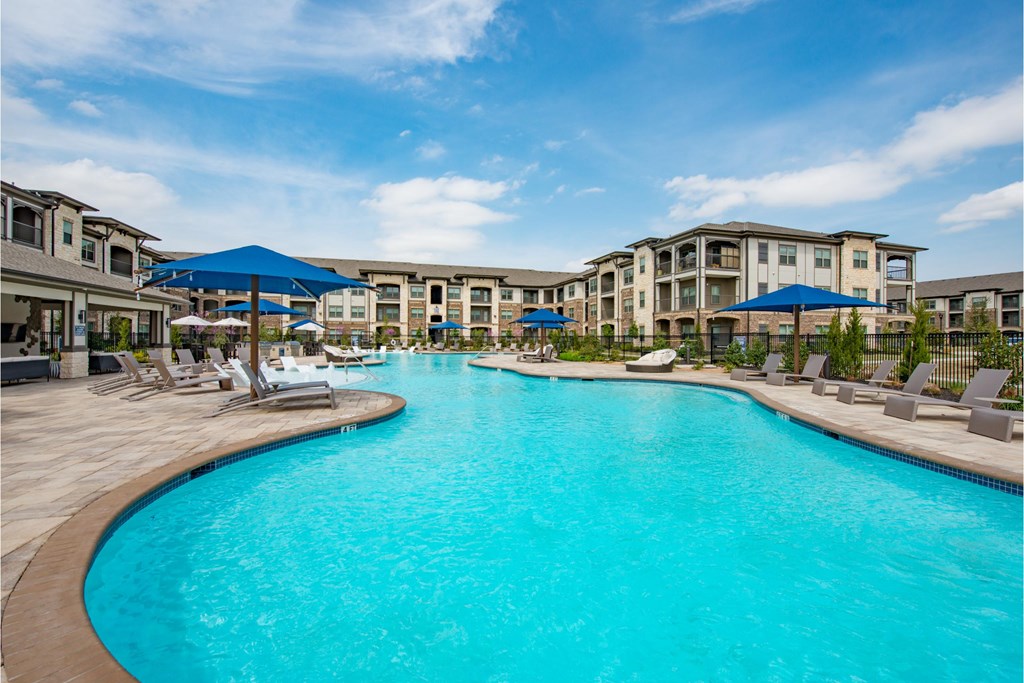 a large swimming pool with umbrellas in front of a hotel