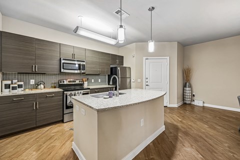 A kitchen with a white counter top and wooden floors.