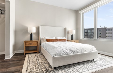 A bedroom with a large bed and a window overlooking a cityscape.
