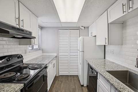 A kitchen with a black stove top oven and white cabinets.