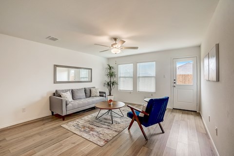 Well-lit living room featuring abundant natural lighting, accentuated by a door that opens to the backyard