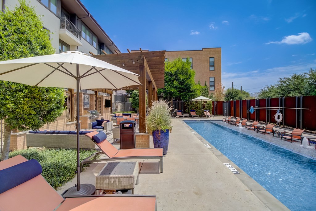 a pool with lounge chairs and umbrellas next to a building