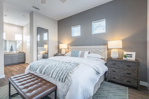 A bedroom with a large bed, a bench, and a dresser.
