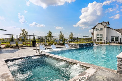 A pool with hot tub, and building in the background.