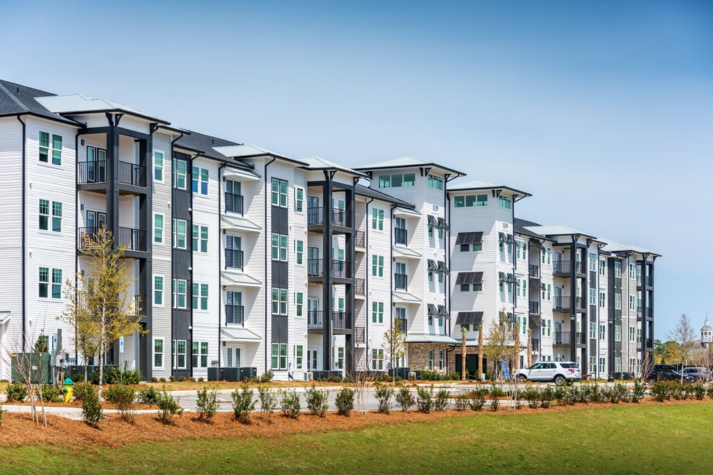 A row of modern apartment buildings with green lawns in front.