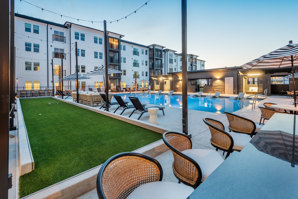 A poolside area with chairs and a building in the background.