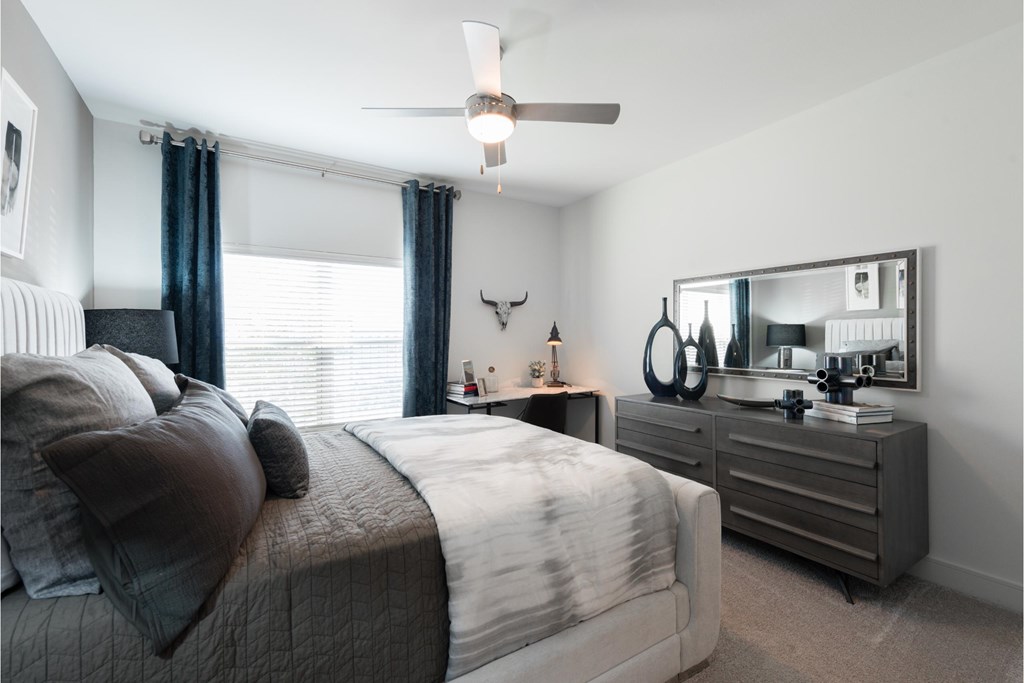 a bedroom with a bed and dresser and a ceiling fan