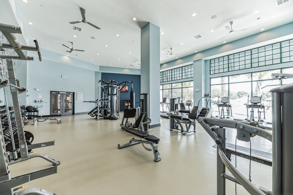 a workout room with weights and other exercise equipment in a building with large windows