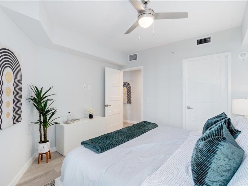 a white bedroom with a bed and a ceiling fan