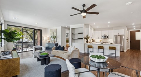 A modern living room with a ceiling fan and a dining table with chairs.