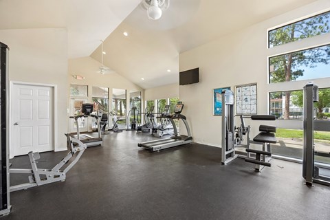 A spacious gym with a variety of equipment and a view of the outdoors through large windows.