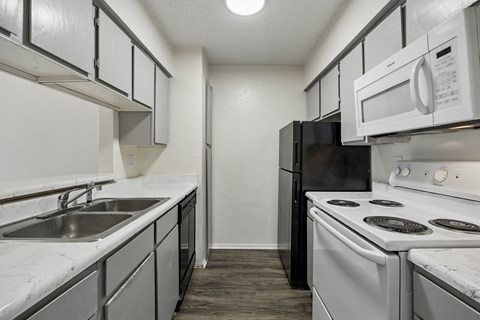 A kitchen with black and white appliances and a marble counter.