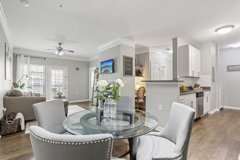 A modern dining room with a glass table and grey chairs.