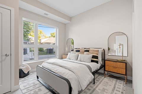 A bedroom with a large bed and a view of the street outside the window.