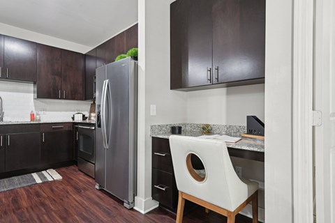 A kitchen with a white chair and a refrigerator.