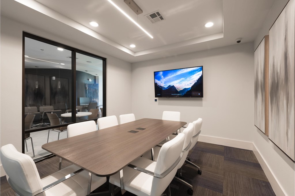 a conference room with a table and chairs and a tv on the wall