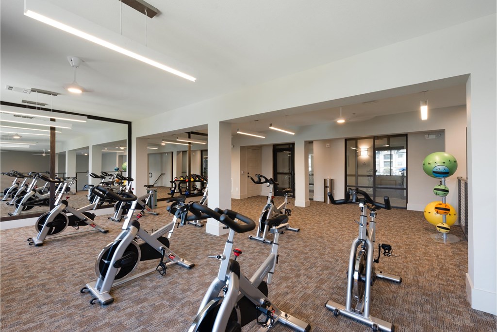 a gym with various exercise bikes and weights in a large room