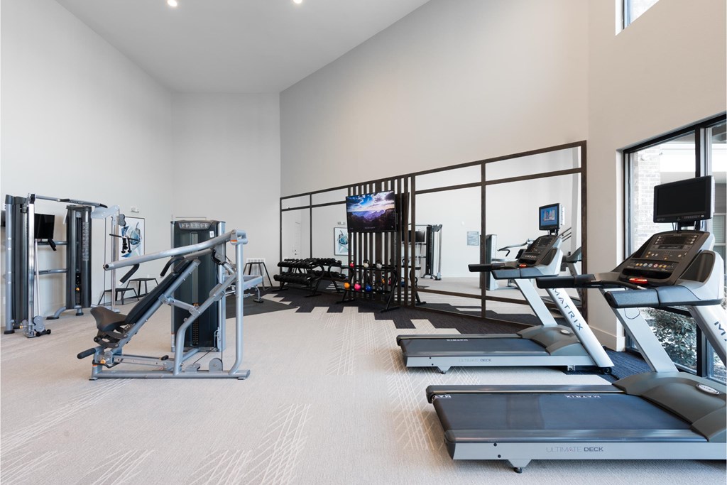 a gym with treadmills and weights and a tv