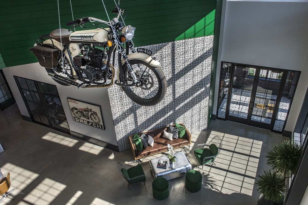 A motorcycle is hanging from the ceiling in a room with a green wall and a sign that reads