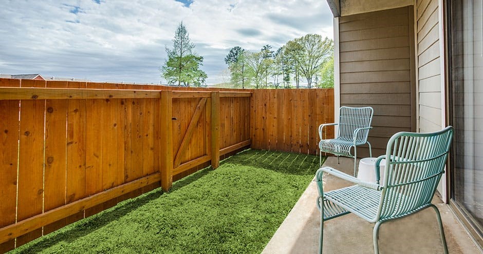 a patio with two chairs and a fence