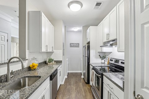 A kitchen with white cabinets and a granite countertop.