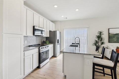 A modern kitchen with white cabinets and stainless steel appliances.