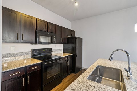 A kitchen with black cabinets and a granite countertop.