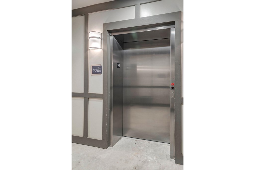 a stainless steel elevator in a building with glass doors