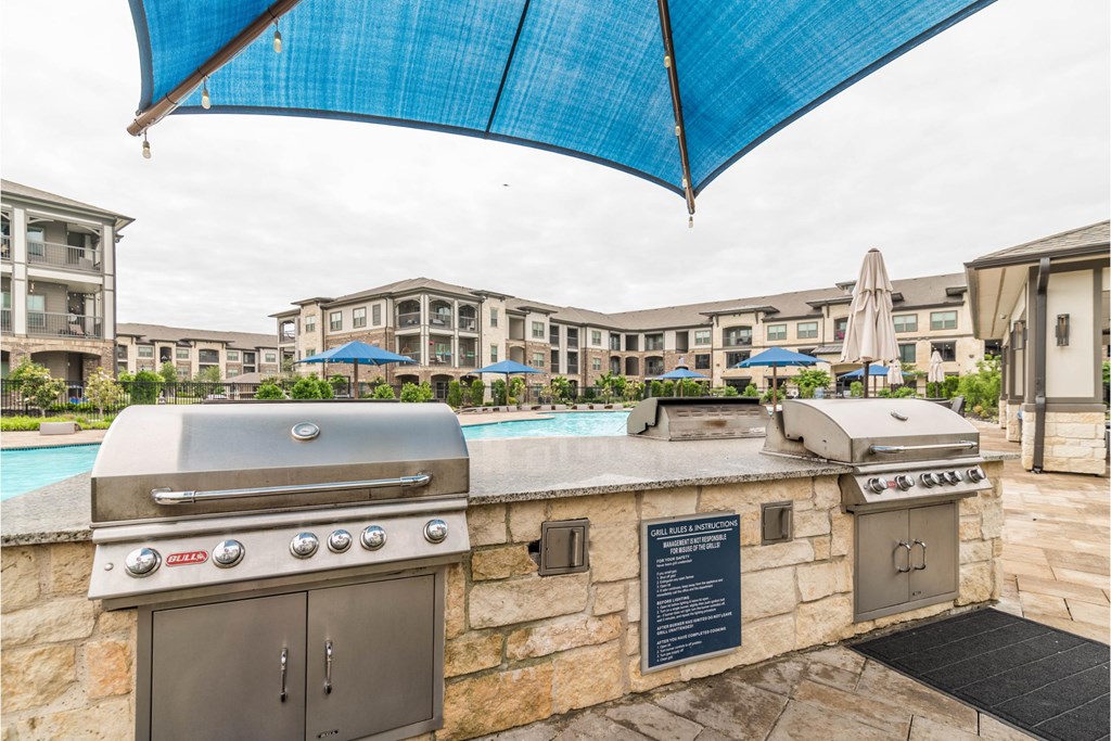 a backyard with a grill and a pool with apartments in the background