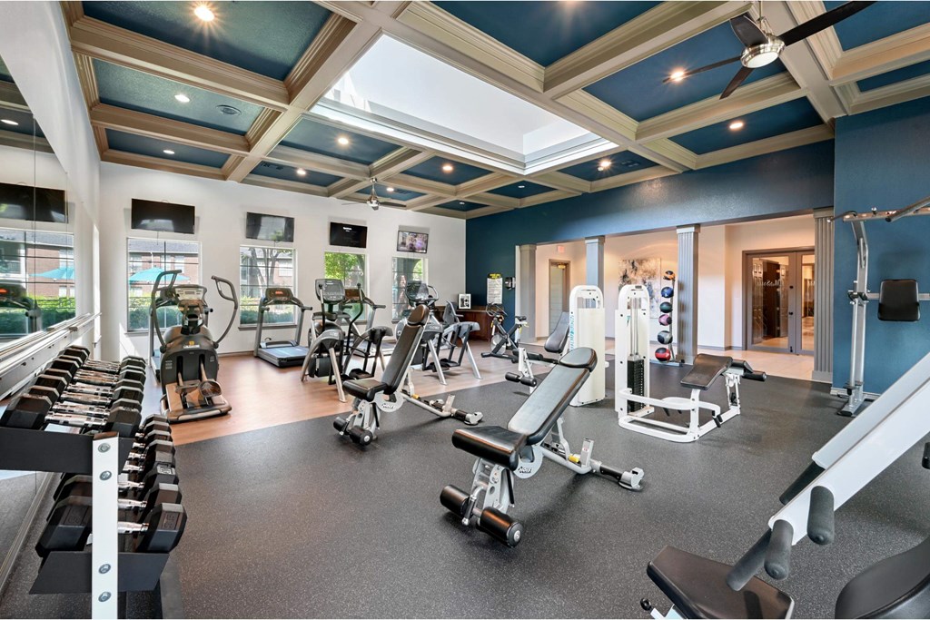 a gym with cardio equipment and weights in a building with blue ceilings