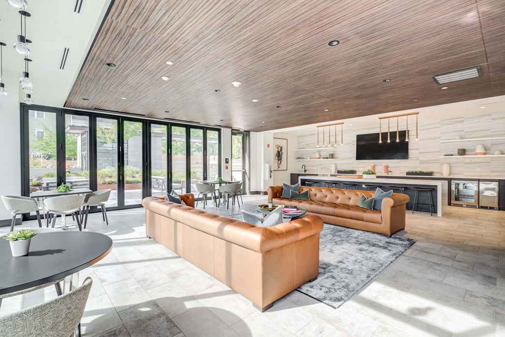 A modern living room with a tan sofa and a wooden ceiling.