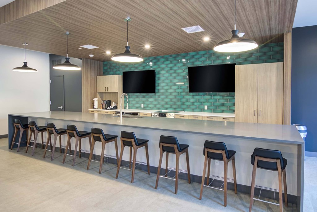 A bar with stools and a green patterned backsplash.