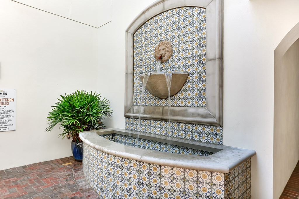 a tiled fountain in a room with a window and a plant