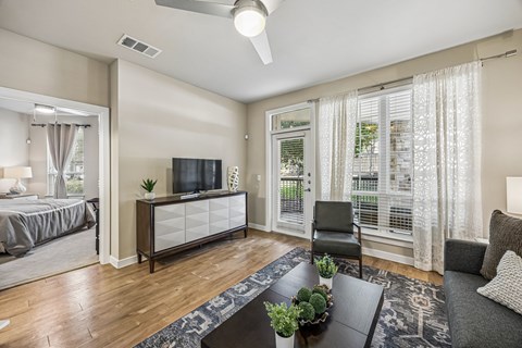 A living room with a television, a chair, and a table with a plant on it.