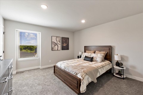 A bedroom with a large bed and a window with blinds.