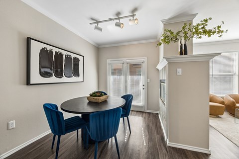 A dining room with a round table and blue chairs.