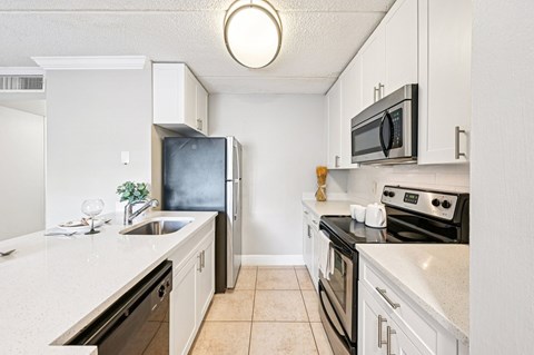 A kitchen with white cabinets and black appliances.