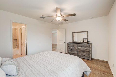 Rustic bedroom featuring hardwood floors, a ceiling fan for added comfort, and convenient access to a private bathroom, combining charm with practicality in a cozy setting.