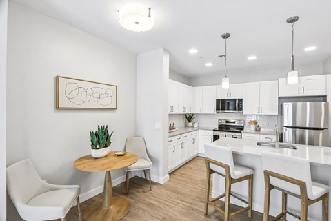 A kitchen with a white chair and a table with a plant on it.