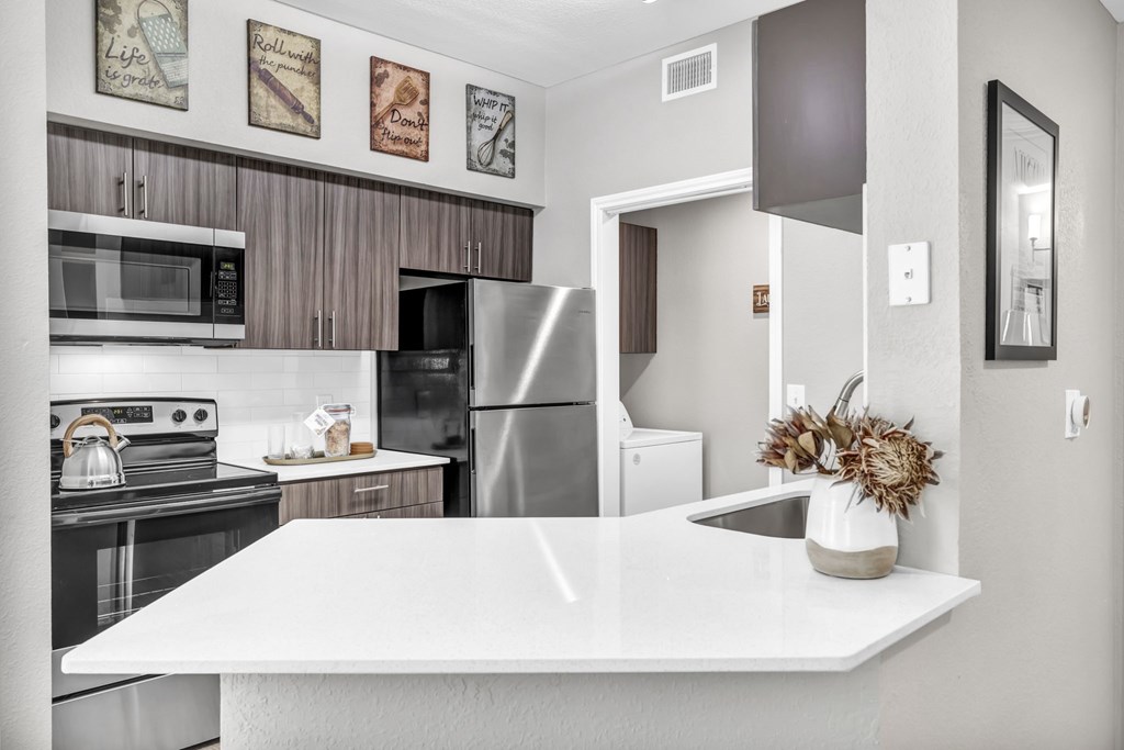 a kitchen with white countertops and stainless steel appliances