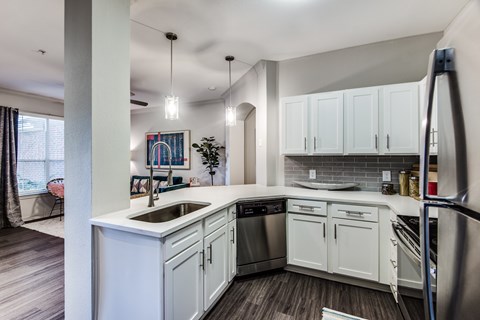 A modern kitchen with white cabinets and stainless steel appliances.