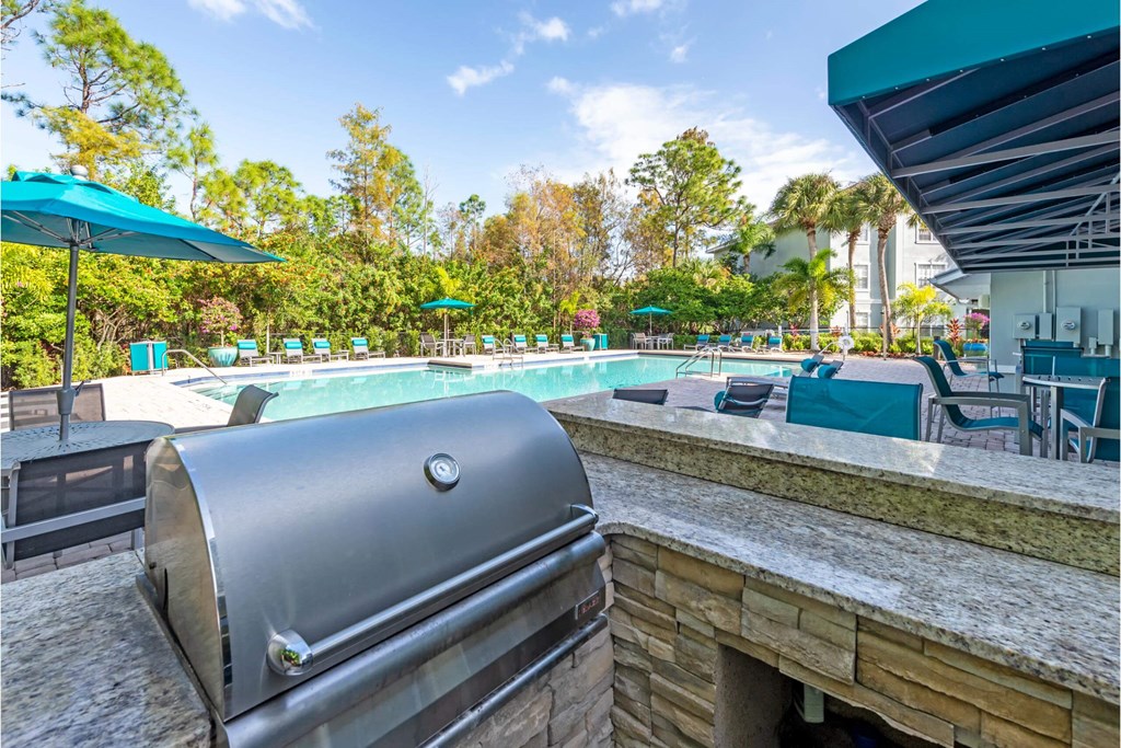 a pool with a grill and a swimming pool with umbrellas