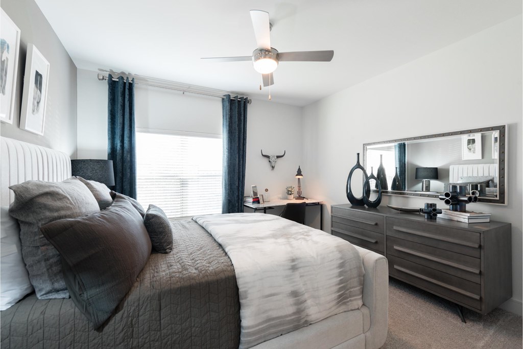 a bedroom with a bed and dresser and a ceiling fan